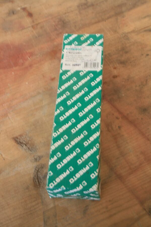 Boîte cartonnée verte Presto scellée sous film, garniture de robinetterie pour urinoir Selles 841A, posée sur une table en bois