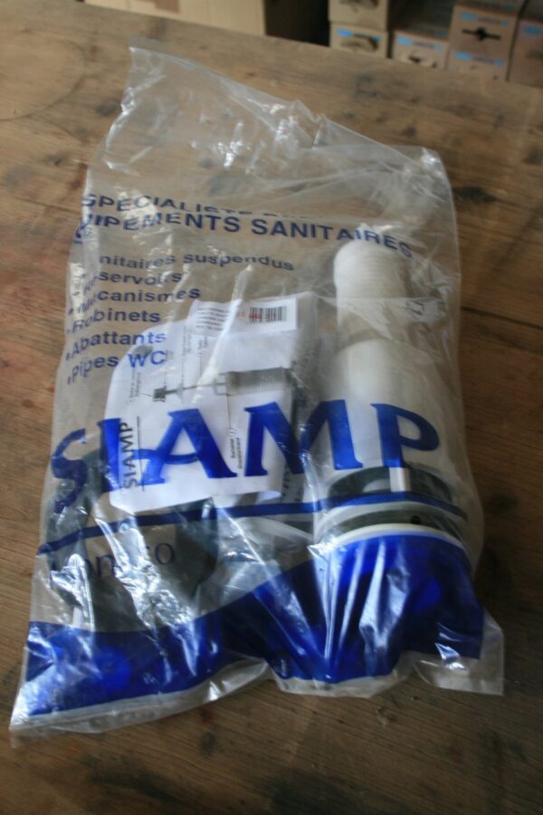 Sachet scellé SIAMP contenant un mécanisme de chasse d'eau à tirette chromé, posé sur un établi en bois