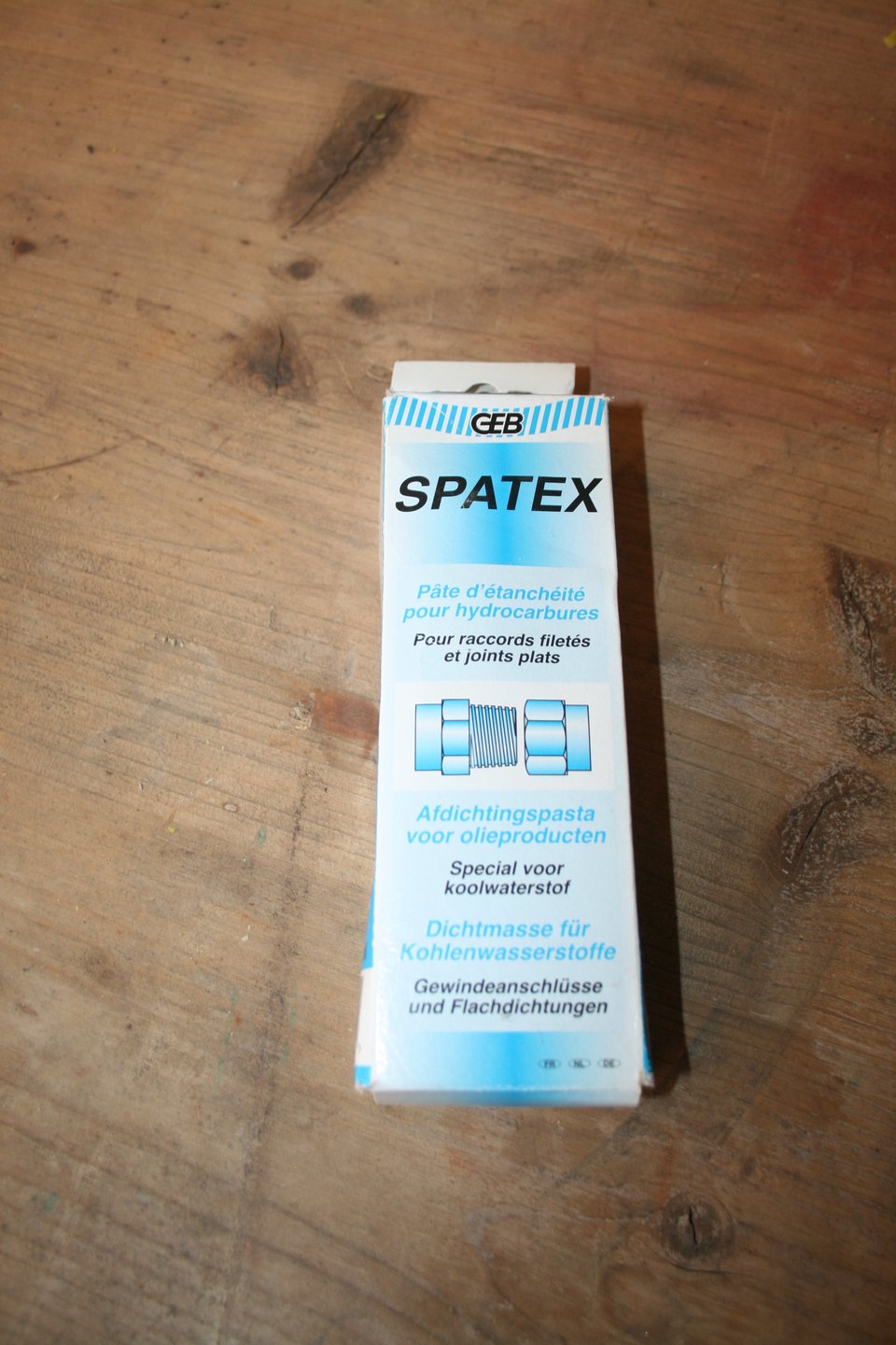 Boîte de pâte d'étanchéité GEB Spatex pour raccords filetés, posée sur un plan de travail en bois