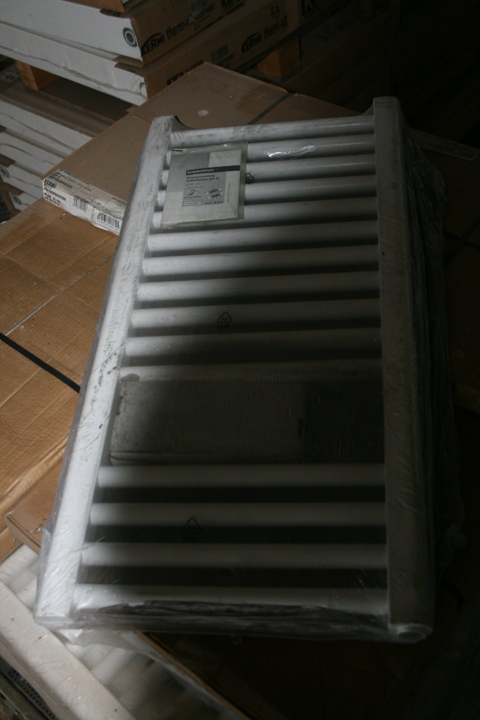 Radiateur design Kermi B24 S blanc emballé sous film, posé sur des cartons en entrepôt