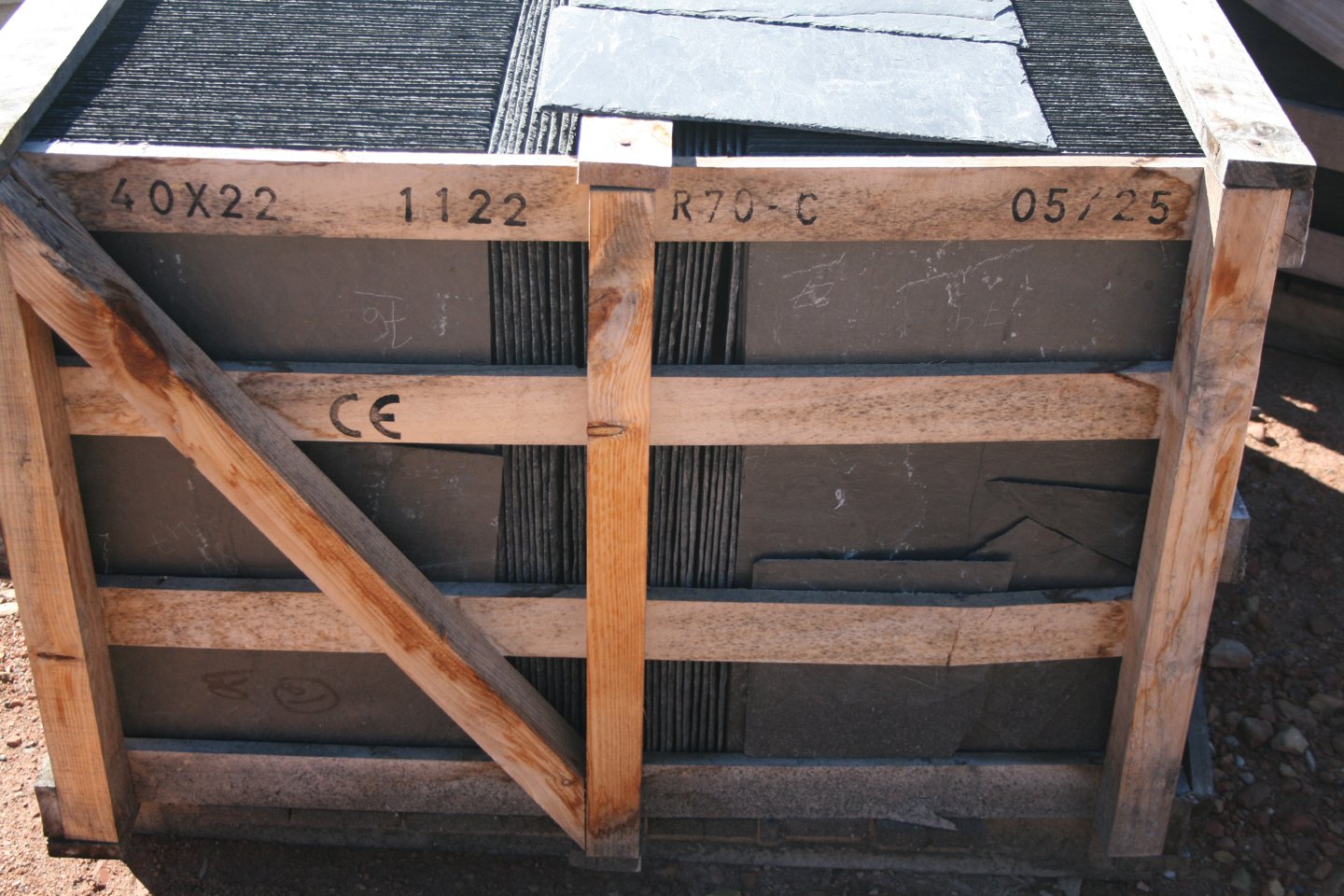Palette d'ardoises naturelles 40 x 22 cm empilées sur chant dans une cage en bois, avec le marquage 40X22 tamponné à l'encre sur la latte