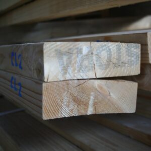 Bouts de pièces de bois d'ossature empilées, marquage bleu CL2 sur le chant et fentes fines sur les têtes