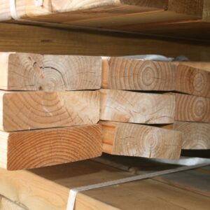 Paquets de pièces de bois de structure empilées et cerclées, avec l'inscription 3M au marqueur sur la pièce du dessus