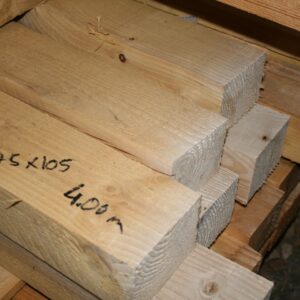 Pile de chevrons en bois brut avec la section 75x105 et la longueur 4,00 m écrites au marqueur noir sur la pièce du premier plan